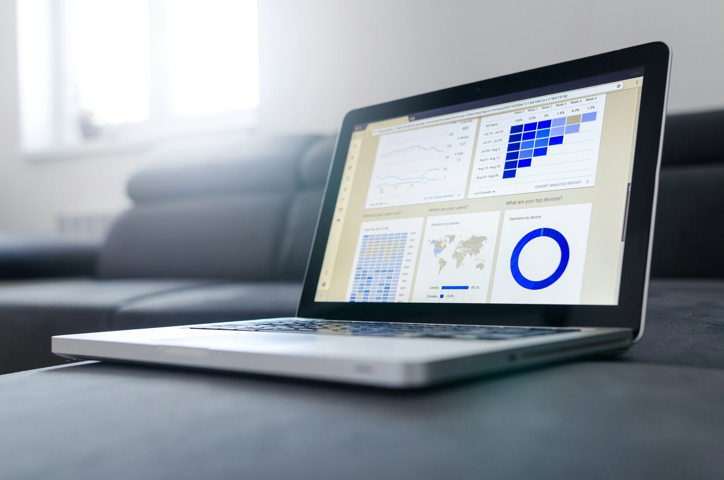 An open laptop displaying an analytics dashboard of line charts, a shaded grid and a segmented ring